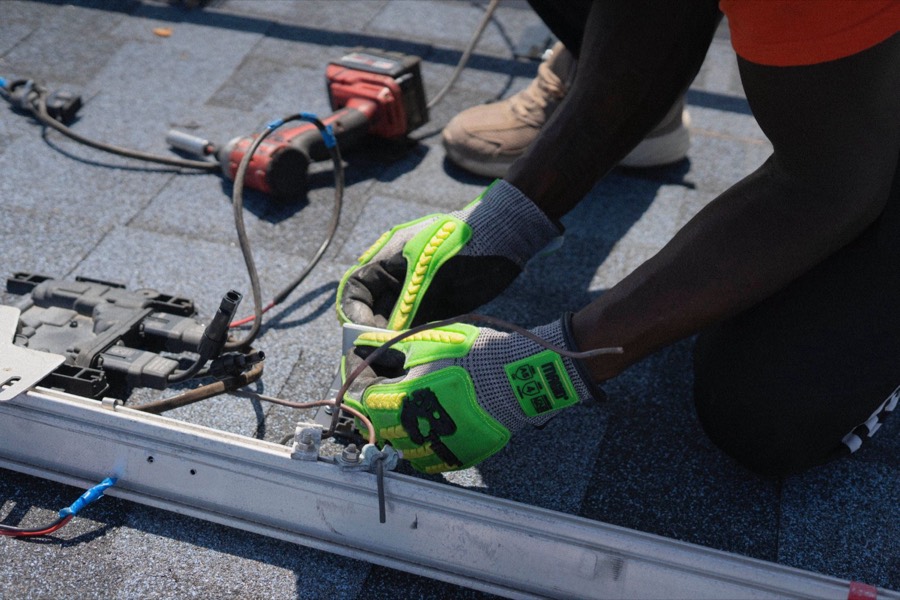 Technician in safety gloves connecting a solar panel on a rooftop